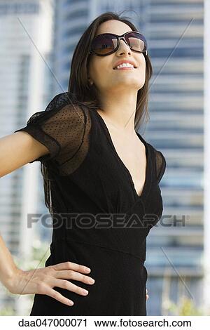 Woman dressed in black clothing and sunglasses, looking up and smiling View Large Photo Image Stock Image - Woman dressed in black clothing and sunglasses, looking up and smiling. Fotosearch
