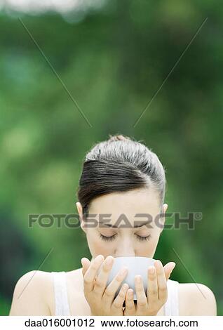 Stock Image - Woman drinking from bowl. Fotosearch