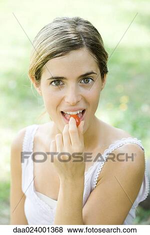 Woman eating cherry tomato, looking at camera, portrait View Large Photo Image Stock Photo - Woman eating cherry tomato, looking at camera, portrait. Fotosearch