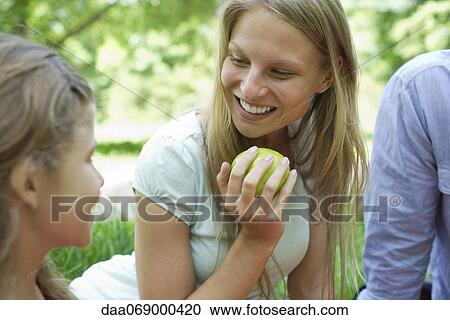 Stock Image - Woman enjoying picnic with her family. Fotosearch
