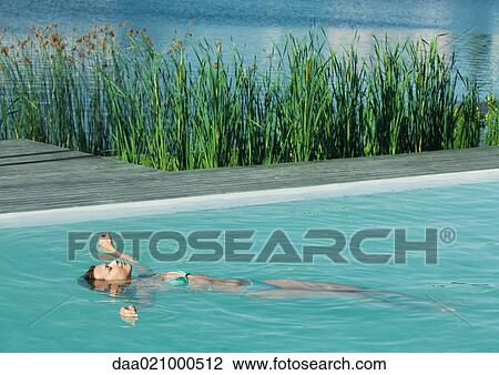 Woman floating on back in pool, full length, lake in background View Large Photo Image Stock Image - Woman floating on back in pool, full length, lake in background. Fotosearch