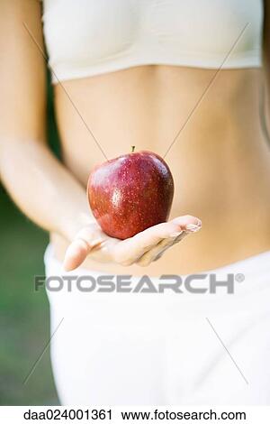 Woman holding apple in front of bare abdomen, close-up of mid section View Large Photo Image Stock Image - Woman holding apple in front of bare abdomen, close-up of mid section. Fotosearch
