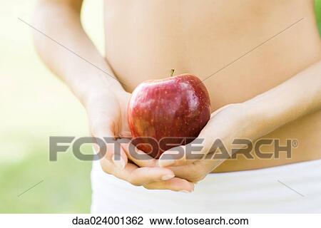 Woman holding apple in front of bare abdomen, close-up of mid section View Large Photo Image Stock Image - Woman holding apple in front of bare abdomen, close-up of mid section. Fotosearch
