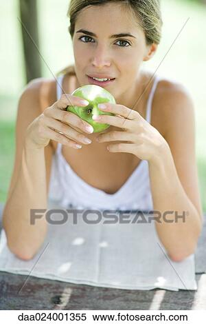 Woman holding apple, looking at camera View Large Photo Image Stock Photography - Woman holding apple, looking at camera. Fotosearch