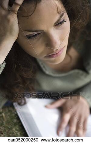 Stock Image - Woman holding book, looking away in distraction. Fotosearch
