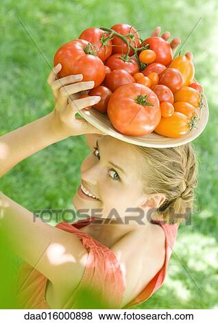 Stock Photo - Woman holding bowl full of tomatoes on top of head. Fotosearch