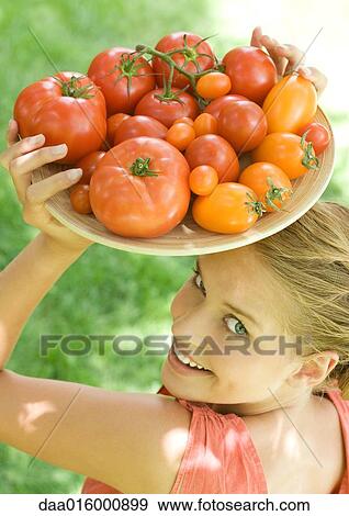 Stock Photo - Woman holding bowl full of tomatoes on top of head. Fotosearch