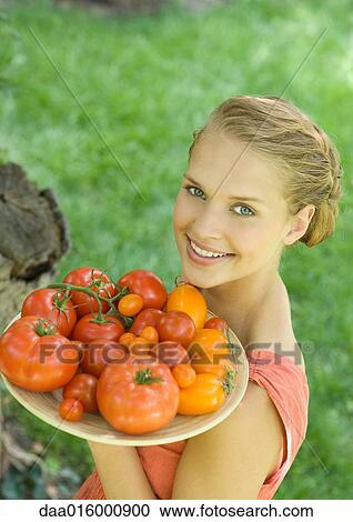 Stock Image - Woman holding bowl full of tomatoes. Fotosearch