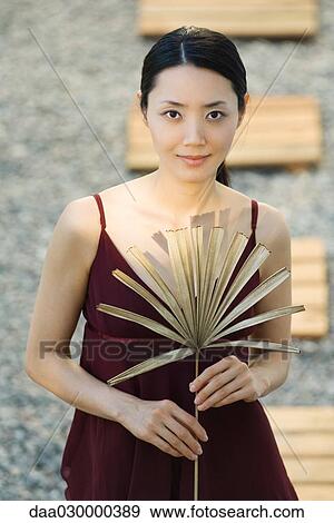 Woman holding dried palm leaf, smiling at camera View Large Photo Image Stock Photo - Woman holding dried palm leaf, smiling at camera. Fotosearch
