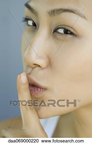 Woman holding finger against lips, portrait View Large Photo Image Stock Image - Woman holding finger against lips, portrait. Fotosearch
