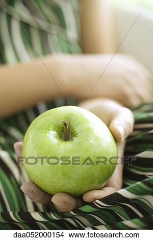 Picture - Woman holding green apple, cropped. Fotosearch
