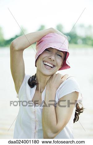 Woman holding hat on top of head, laughing, portrait View Large Photo Image Stock Image - Woman holding hat on top of head, laughing, portrait. Fotosearch