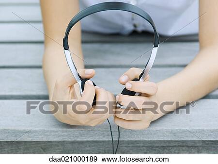 Woman holding headphones, close-up View Large Photo Image Stock Photo - Woman holding headphones, close-up. Fotosearch