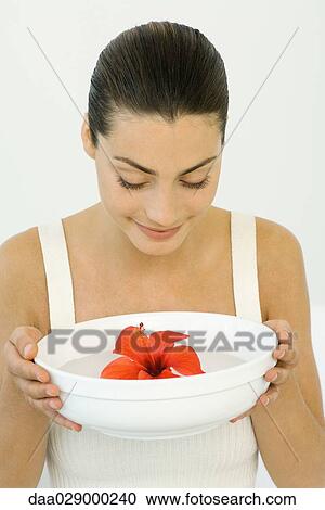 Woman holding hibiscus blossom in bowl of water, looking down, smiling View Large Photo Image Stock Image - Woman holding hibiscus blossom in bowl of water, looking down, smiling. Fotosearch