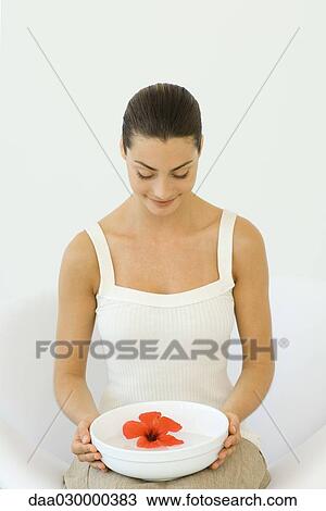 Woman holding hibiscus blossom in bowl of water, looking down, smiling View Large Photo Image Stock Image - Woman holding hibiscus blossom in bowl of water, looking down, smiling. Fotosearch