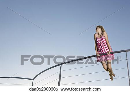 Woman holding on to railing, looking away, low angle view View Large Photo Image Stock Photography - Woman holding on to railing, looking away, low angle view. Fotosearch