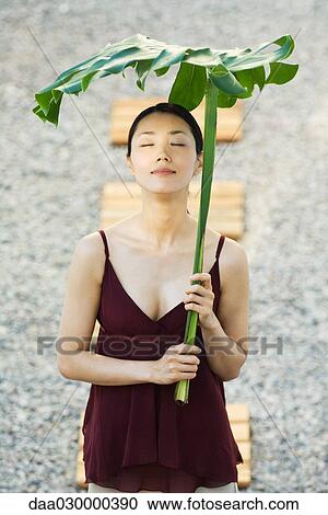 Woman holding palm leaf over her head, eyes closed, smiling View Large Photo Image Stock Image - Woman holding palm leaf over her head, eyes closed, smiling. Fotosearch