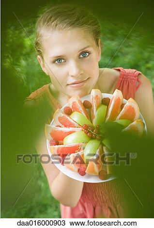 Woman holding plate full of fruit slices, high angle view View Large Photo Image Stock Image - Woman holding plate full of fruit slices, high angle view. Fotosearch