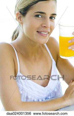 Woman holding up glass of orange juice, smiling at camera View Large Photo Image Stock Photograph - Woman holding up glass of orange juice, smiling at camera. Fotosearch
