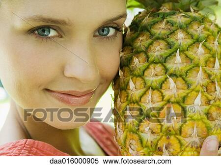 Woman holding up pineapple to face View Large Photo Image Stock Photography - Woman holding up pineapple to face. Fotosearch