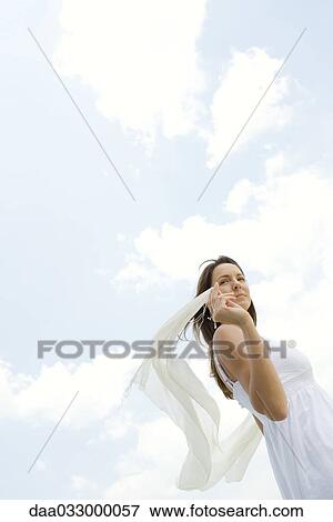 Woman holding up shawl outdoors, tousled by wind, low angle view View Large Photo Image Stock Photo - Woman holding up shawl outdoors, tousled by wind, low angle view. Fotosearch
