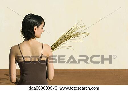 Woman holding wheat, rear view View Large Photo Image Stock Photograph - Woman holding wheat, rear view. Fotosearch