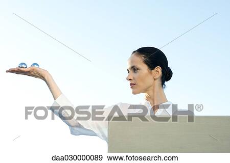 Stock Photo - Woman holding yin yang balls in hand, low angle view. Fotosearch