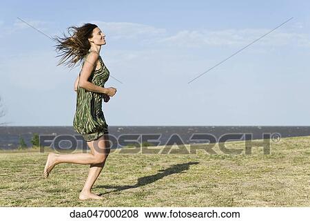 Woman in dress running across grass, barefoot View Large Photo Image Stock Photo - Woman in dress running across grass, barefoot. Fotosearch