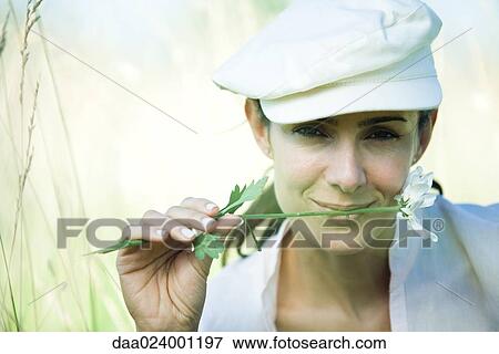 Woman in field, holding flower between lips View Large Photo Image Stock Photo - Woman in field, holding flower between lips. Fotosearch