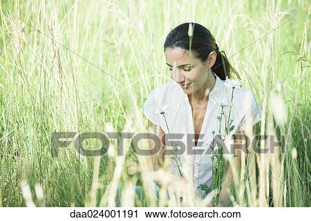 Stock Image - Woman in field, looking down. Fotosearch