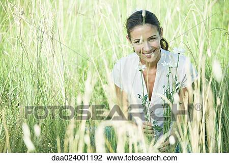Stock Image - Woman in field, smiling at camera. Fotosearch