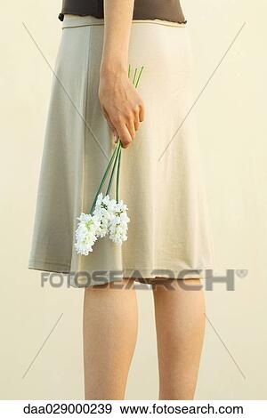 Woman in skirt holding flowers, cropped view View Large Photo Image Stock Photo - Woman in skirt holding flowers, cropped view. Fotosearch
