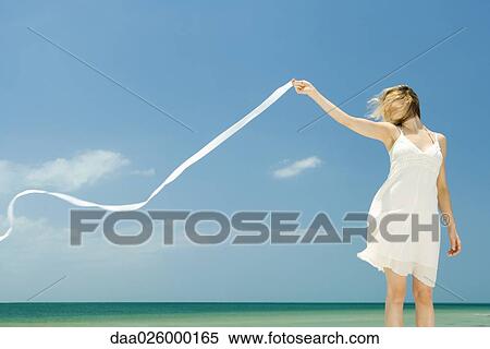 Woman in sundress holding up ribbon in breeze, hair covering face View Large Photo Image Stock Photography - Woman in sundress holding up ribbon in breeze, hair covering face. Fotosearch
