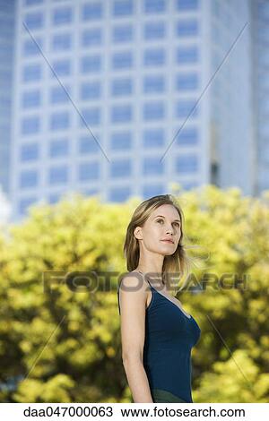 Stock Image - Woman in tank top standing outdoors, portrait. Fotosearch