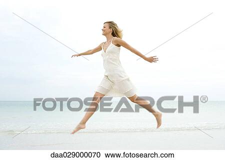 Woman jumping at the beach, arms out, side view View Large Photo Image Stock Image - Woman jumping at the beach, arms out, side view. Fotosearch