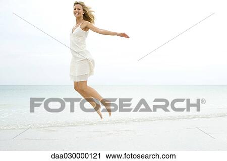 Woman jumping in the air at the beach, smiling at camera View Large Photo Image Stock Image - Woman jumping in the air at the beach, smiling at camera. Fotosearch