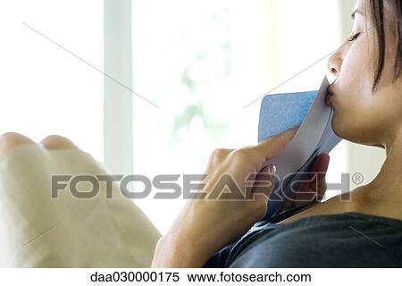 Stock Photography - Woman kissing letter in envelope, side view. Fotosearch