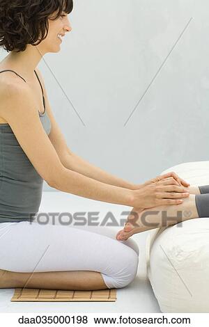 Woman kneeling at foot of futon massaging another woman's feet View Large Photo Image Stock Photo - Woman kneeling at foot of futon massaging another woman's feet. Fotosearch