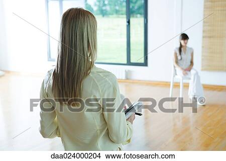 Picture - Woman leading group therapy session, rear view, cropped. Fotosearch