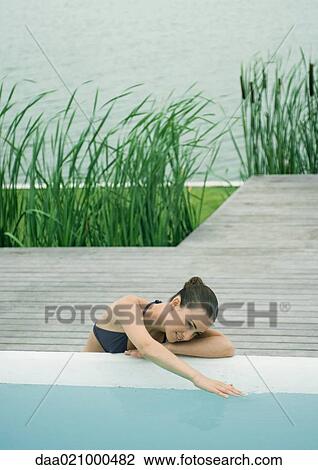 Woman leaning against edge of pool, touching surface of water, lake in background View Large Photo Image Stock Image - Woman leaning against edge of pool, touching surface of water, lake in background. Fotosearch
