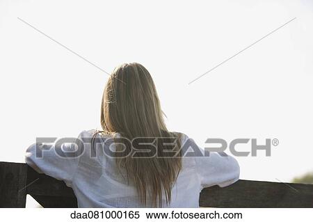Stock Photography - Woman leaning against railing, rear view. Fotosearch