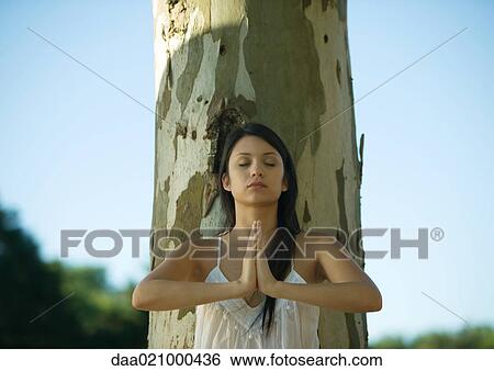 Woman leaning against tree, doing yoga pose View Large Photo Image Stock Photograph - Woman leaning against tree, doing yoga pose. Fotosearch