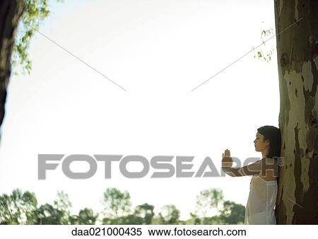 Woman leaning against tree, doing yoga pose View Large Photo Image Stock Photography - Woman leaning against tree, doing yoga pose. Fotosearch