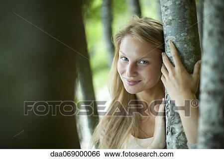 Woman leaning against tree trunk, portrait View Large Photo Image Stock Photograph - Woman leaning against tree trunk, portrait. Fotosearch