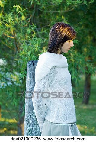 Stock Photograph - Woman leaning against wooden post, eyes closed. Fotosearch