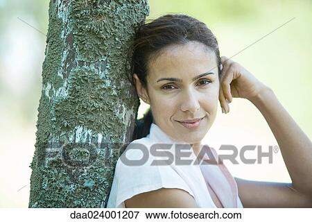 Woman leaning against wooden post, looking at camera, head and shoulders View Large Photo Image Stock Photo - Woman leaning against wooden post, looking at camera, head and shoulders. Fotosearch