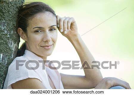 Woman leaning against wooden post, looking at camera, head and shoulders View Large Photo Image Stock Photograph - Woman leaning against wooden post, looking at camera, head and shoulders. Fotosearch