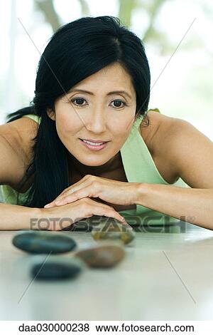 Woman leaning forward, arranging pebbles, smiling View Large Photo Image Stock Photo - Woman leaning forward, arranging pebbles, smiling. Fotosearch