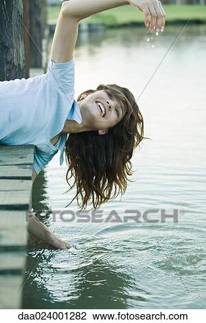 Woman leaning off edge of dock, getting hands wet View Large Photo Image Stock Image - Woman leaning off edge of dock, getting hands wet. Fotosearch