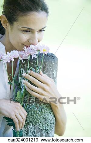 Woman leaning on wooden post, smelling flowers View Large Photo Image Stock Photo - Woman leaning on wooden post, smelling flowers. Fotosearch